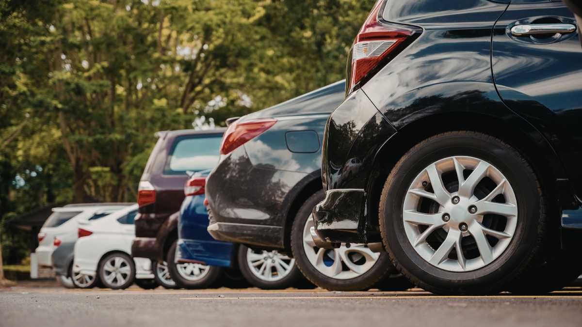 Meccanico che controlla un'auto durante una revisione, con documenti e strumenti sul tavolo.